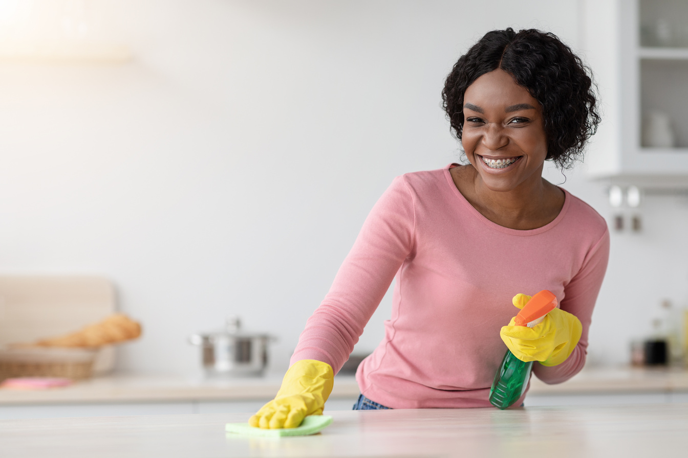 Happy african american woman house-keeper cleaning table